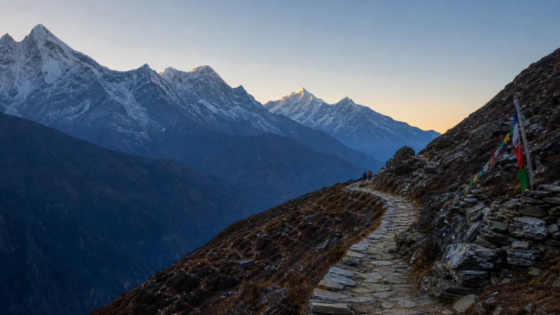 A stone trekking trail leading toward snow-covered Himalayan peaks at first light